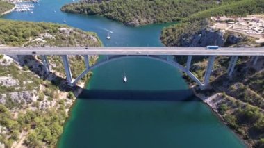 Hırvatistan, Orta Avrupa 'da yaz güneşli bir günde Krka nehri, otostrada ve kemer köprüsünün üzerinde uçmak, seyahat ve doğa kavramı. Güzel manzara ve büyük köprüsü olan mavi deniz. Havadan panorama görünümü