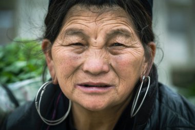 Sapa, Vietnam - Mart 06, 2020: Geleneksel kıyafet ve mücevher giyen etnik Hmong kadını turistlerin Sapa, Kuzey Vietnam 'daki dağ köyünde el sanatları satmalarını bekliyor