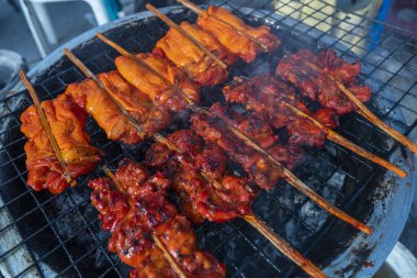 Tayland 'da Koh Phangan adasındaki bir gece marketinde odun sopasıyla ızgarada ızgara tavuk eti, yakın.