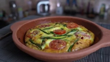 Sebzeli frittata ile seramik kase, basit vejetaryen yemeği. Yumurtalı frittata, domates, biber, soğan, peynir ve yeşil sarımsak yaprakları masada, döndür, kapat. Sağlıklı yumurta omleti.