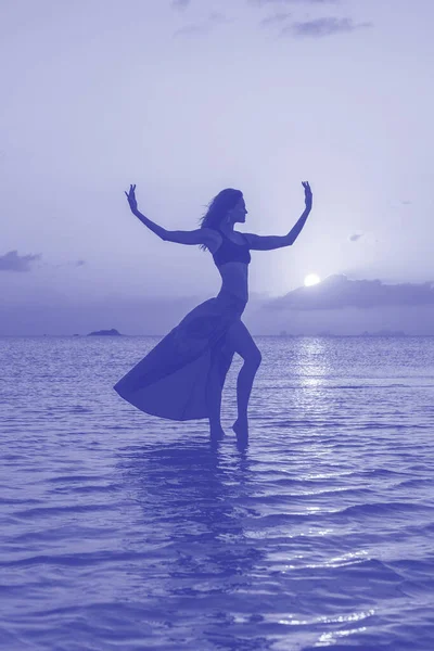 日落时分 年轻的美女在热带海滩上的海水边跳舞 夏天的概念 假日旅行 2022年的流行色彩 超紫罗兰的创作和情绪色彩的图片 — 图库照片