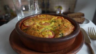 Sebzeli frittata ile seramik kase, basit vejetaryen yemeği. Yumurtalı frittata, domates, biber, soğan, peynir ve yeşil sarımsak yaprakları masada, döndür, kapat. Sağlıklı yumurta omleti.
