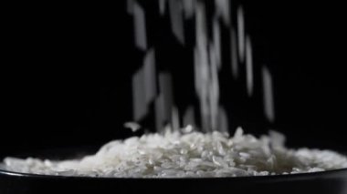 Beyaz pirinç yere düşer ve kaseyi masaya koyar, kapat. Siyah arka planda çekim yapmak. Yavaş çekim