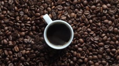 Beyaz kahve fincanı taze kavrulmuş kahve çekirdekleri, yakın plan, üst manzara. 360 derece dönüş. Döngü hareketi
