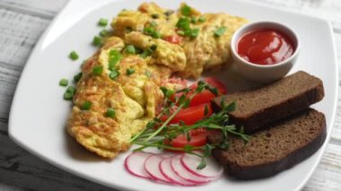 Beyaz ahşap zemin üzerinde soğan, domates, biber, yumurta ve peynirle doldurulmuş omlet ve çatal. Kahvaltı için sağlıklı diyet yemeği. Lezzetli sabah yemeği. Üst görünüm, kapat, döndür