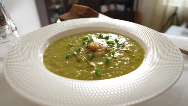 テーブルの上にスパイスで白いプレートに緑のエンドウ豆のクリームスープ 閉じます 健康食品 おいしい乾燥した緑のエンドウ豆のスープ — ストック動画