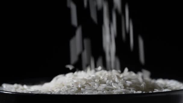白い米が落ち テーブルの上のボウルを埋め 閉じます 黒を背景に撮影 スローモーション — ストック動画
