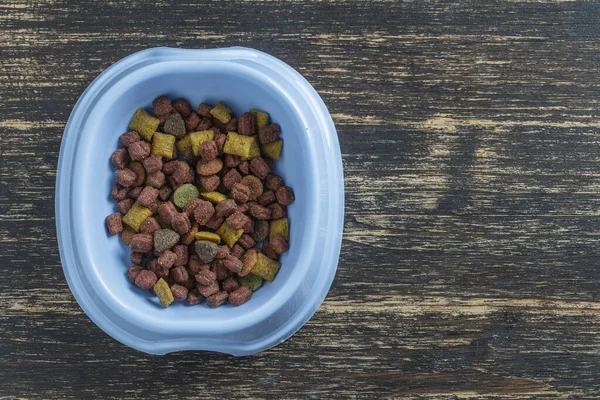 Kedi kurutulmuş gıdalar ahşap arka planda mavi plastik bir kasede, üst manzara, kapat, boşluğu kopyala