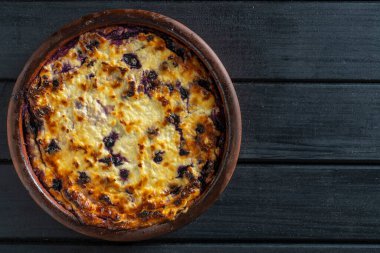 Yabanmersinli süzme peynir güveci, yakın çekim. Siyah masada taze böğürtlenli kremalı güveç. Üst görünüm, alanı kopyala