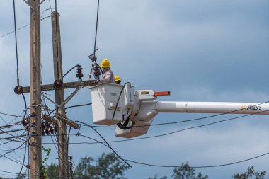 Koh Phangan, Tayland - Jan, 26, 2022: Gezici vinç kovasında duran iki erkek elektrikçi Tayland 'ın Koh Phangan adasındaki elektrik hattının kablosunu tamir ediyor