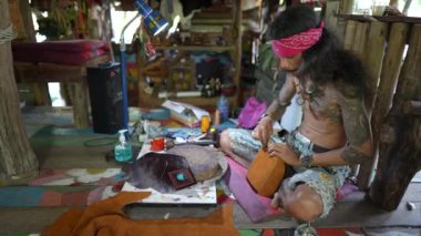 Koh Phangan, Tayland - Şubat, 06, 2022: Taylandlı zanaatkar Koh Phangan, Tayland 'da bir sokak pazarında deri çantalar dikiyor.