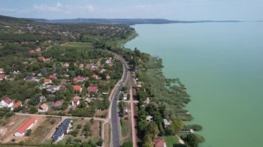Balaton Gölü, Macaristan - 22 Ağustos 2021: Balaton Gölü 'nün havadan görünüşü, Macaristan' daki su gölü, evler, tarlalar ve bahçeler boyunca arabalı yol