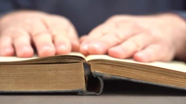 Evde ya da kütüphanede kitap okuyan bir adamın eli. Eski bir kitabın sayfalarını çevirip kapat.
