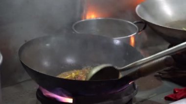 Malezyalı erkek satıcı, Malezya 'nın Borneo Adası, Kota Kinabalu' daki gece pazarında büyük bir kızartma tavasında sokak yemekleri pişiriyor.