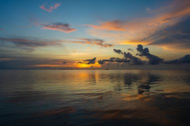 Tayland 'daki Koh Phangan adasında deniz suyunun üzerinde güzel bir günbatımı. Seyahat ve doğa kavramı. Akşam gökyüzü, bulutlar, güneş ve deniz suyu. Denizin üzerinde harika bir bulut