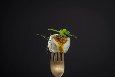 Yumuşak haşlanmış yumurta bezelye mikroyeşili ve hardallı siyah arka planda bir çatal, yakın plan, kahvaltı zamanı.