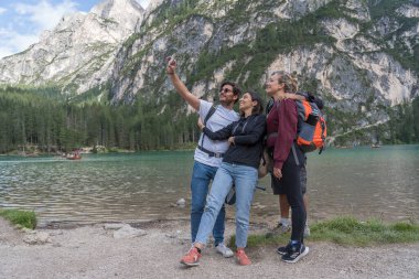 Lago di Braies, İtalya - 26 Ağustos 2021: Bir grup genç turist, Braies Gölü 'nün arka planında kendi fotoğraflarını çekiyor.