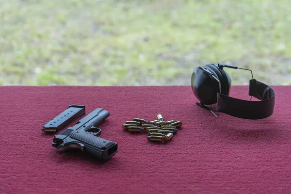 Pistol gun, pistol magazine, headphones and ammo bullets on the table before use in the shooting range, close up