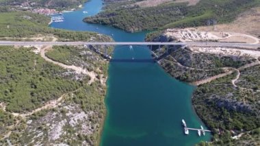 Hırvatistan, Orta Avrupa 'da yaz güneşli bir günde Krka nehri, otostrada ve kemer köprüsünün üzerinde uçmak, seyahat ve doğa kavramı. Güzel manzara ve büyük köprüsü olan mavi deniz. Havadan panorama görünümü