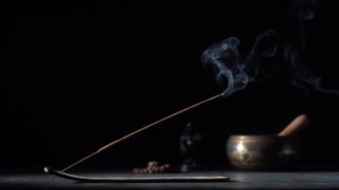Çubuk tutacağındaki Asya tütsü çubuğu siyah arka planda dumanla yanıyor, yakın çekim, kopyalama alanı. Meditasyon, yoga, kişisel gelişim ve ses terapisi kavramı