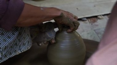 Close-up of a woman potters rotate a wheel with her foot and making a beautiful clay pot with her hands at pottery manufacture in the Old Town Hoi An, Vietnam