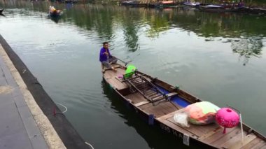 Hoi An, Vietnam - Haziran 05, 2020 Vietnamlı yaşlı kadın Hoi An, Vietnam 'da nehirde yüzen ahşap bir tekne kullanıyor.