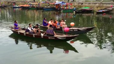 Hoi An, Vietnam - June 05, 2020 : Vietnamese tourists float on a wooden boat on the river along the waterfront in Hoi An old town, Vietnam