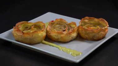 Tabakta servis edilen bir çiçek şeklinde fırında patates, döner, kapar, kapar, siyah arka plan