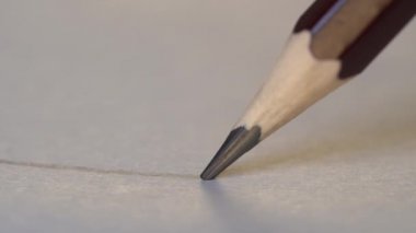 Sanatçı el beyaz kağıda grafit ahşap kalemle düz gri bir çizgi çiziyor. Yaklaş, makro, 4k