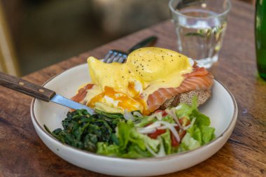 Ekşi ekmek, haşlanmış yumurta, somon, hollandez, sotelenmiş et ve taze sebzeler kafede, kapayın.