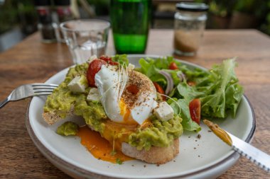 Ekşi ekmek, haşlanmış yumurta, avokado hamuru ve kafede taze sebzeler, kapanış, kahvaltı zamanı.
