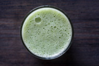 Bir bardak yeşil smoothie, ahşap zemin üzerinde yapraklı bezelye mikroyeşilliklerinden, yakın çekim. Vejetaryen ve sağlıklı beslenme konsepti. Organik yiyecekler. Üst görünüm