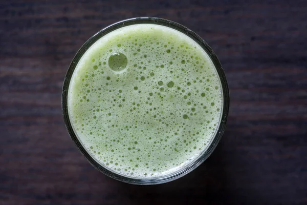 Bir bardak yeşil smoothie, ahşap zemin üzerinde yapraklı bezelye mikroyeşilliklerinden, yakın çekim. Vejetaryen ve sağlıklı beslenme konsepti. Organik yiyecekler. Üst görünüm