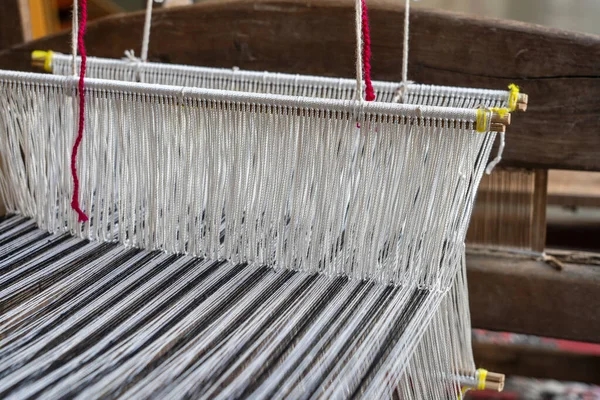 Old hand-weaving vintage wooden loom being used to make fabric, close up, Vietnam