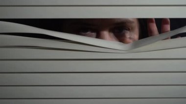 Kapalı alandaki esmer kadının pencereye elleriyle panjur iterken çekilmiş ön portresini kapat. Dışarıdan korkunç görünüyor.