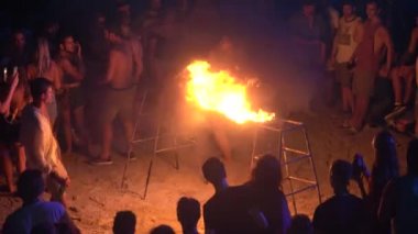 KOH PHANGAN, THAILAND - 21 Şubat 2019: Erkekler ve kızlar gece kumsalda ateşle kavşak altında sürünüyor, Koh Phangan, Tayland 'daki Koh Phangan adasında yangın gösterisi