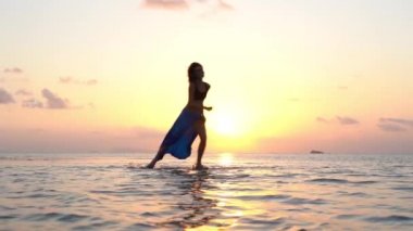 Gün batımında tropik plajın yakınında deniz suyunda dans eden genç bir kız. Yaz kavramı. Tatil seyahati. Koh Phangan Adası, Tayland