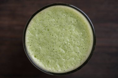 Bir bardak yeşil smoothie, ahşap zemin üzerinde yapraklı bezelye mikroyeşilliklerinden, yakın çekim. Vejetaryen ve sağlıklı beslenme konsepti. Organik yiyecekler. Üst görünüm