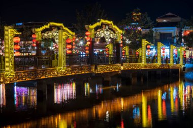 Hoi An, Vietnam - 15 Mart 2020 Hoi An eski kasabasında gece pelerini ve renkli köprü. Hoi An, Vietnam 'ın ortasında Da Nang yakınlarındaki bir şehirdir ve nehir kıyısındaki iyi korunmuş eski kasabasıyla ünlüdür.