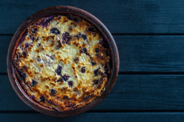 Yabanmersinli süzme peynir güveci, yakın çekim. Siyah masada taze böğürtlenli kremalı güveç. Üst görünüm, alanı kopyala