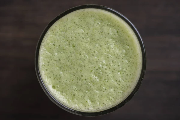 Bir bardak yeşil smoothie, ahşap zemin üzerinde yapraklı bezelye mikroyeşilliklerinden, yakın çekim. Vejetaryen ve sağlıklı beslenme konsepti. Organik yiyecekler. Üst görünüm