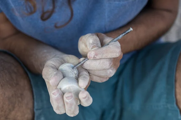 Male hands carve stone sculpture in India, close up