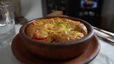 Sebzeli frittata ile seramik kase, basit vejetaryen yemeği. Yumurtalı frittata, domates, biber, soğan, peynir ve yeşil sarımsak yaprakları masada, döndür, kapat. Sağlıklı yumurta omleti.