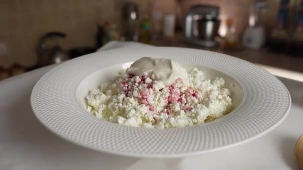 新鲜的自制奶酪与酸奶奶油在一个白色盘子里旋转在桌子上 美味的早餐 — 图库视频影像