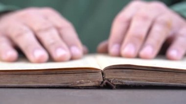 Evde ya da kütüphanede kitap okuyan bir adamın eli. Eski bir kitabın sayfalarını çevirip kapat.