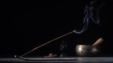 Çubuk tutacağındaki Asya tütsü çubuğu siyah arka planda dumanla yanıyor, yakın çekim, kopyalama alanı. Meditasyon, yoga, kişisel gelişim ve ses terapisi kavramı