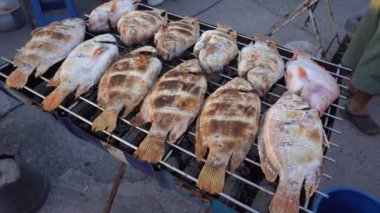 Thai street vendor sells grilled fish at street food market in Koh Phangan, Thailand. Close up