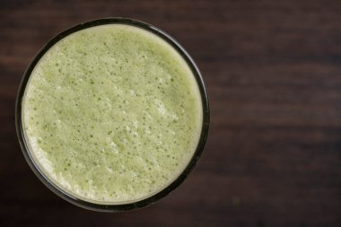Bir bardak yeşil smoothie, ahşap zemin üzerinde yapraklı bezelye mikroyeşilliklerinden, yakın çekim. Vejetaryen ve sağlıklı beslenme konsepti. Organik yiyecekler. Üst görünüm, alanı kopyala