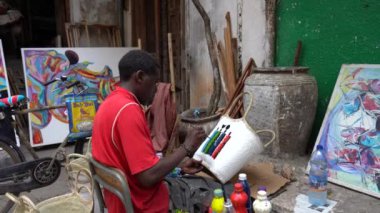 Zanzibar, Tanzania - november 03, 2019 : African man on the street paints a basket for sale for tourists in the Stone Town on the island of Zanzibar, Tanzania, East Africa