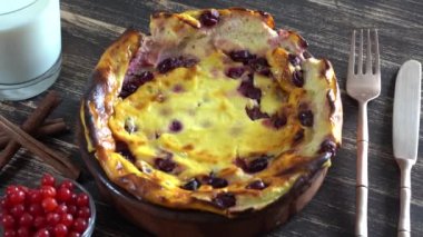 Ahşap masada bektaşi üzümü ve irmikli süzme peynir güveci. Fırında pişmiş peynirli güveç ve sütle seramik kase, kapanıyor, dönüyor.